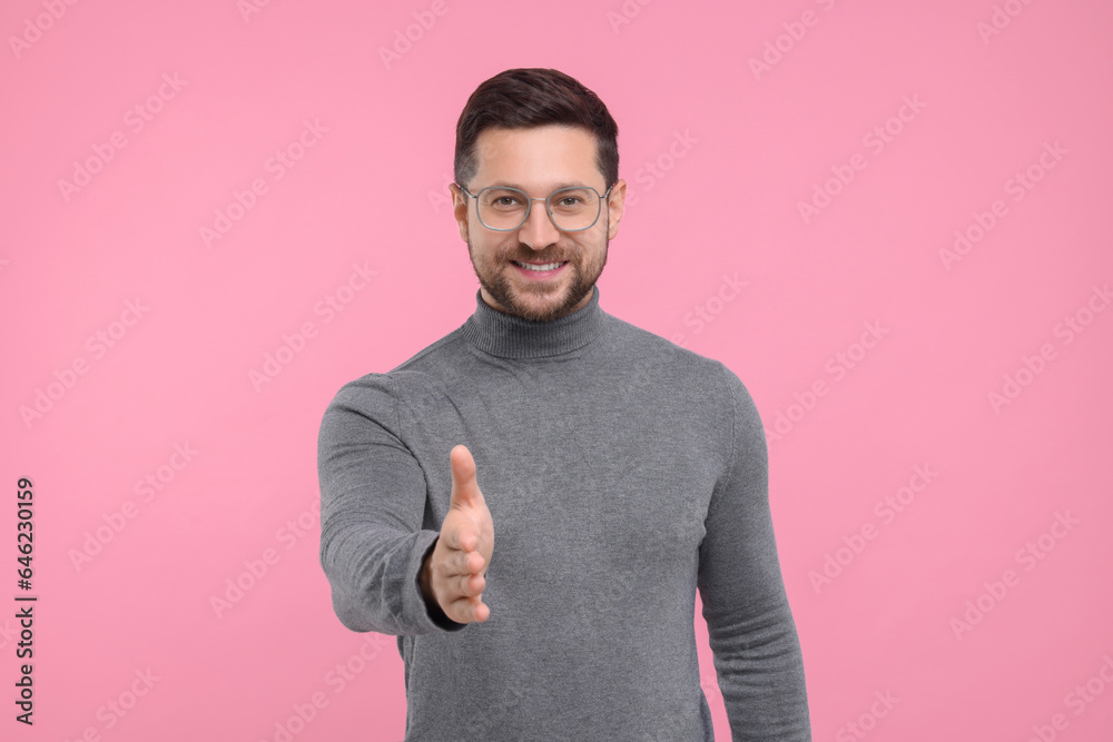 Happy man welcoming and offering handshake on pink background Happy man welcoming and offering handshake on pink background