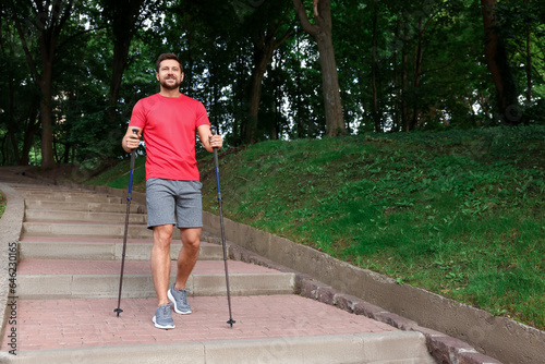 Man practicing Nordic walking with poles on steps outdoors. Space for text