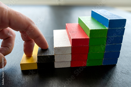 close up of businessman hand climbing upstairs on color wooden block,