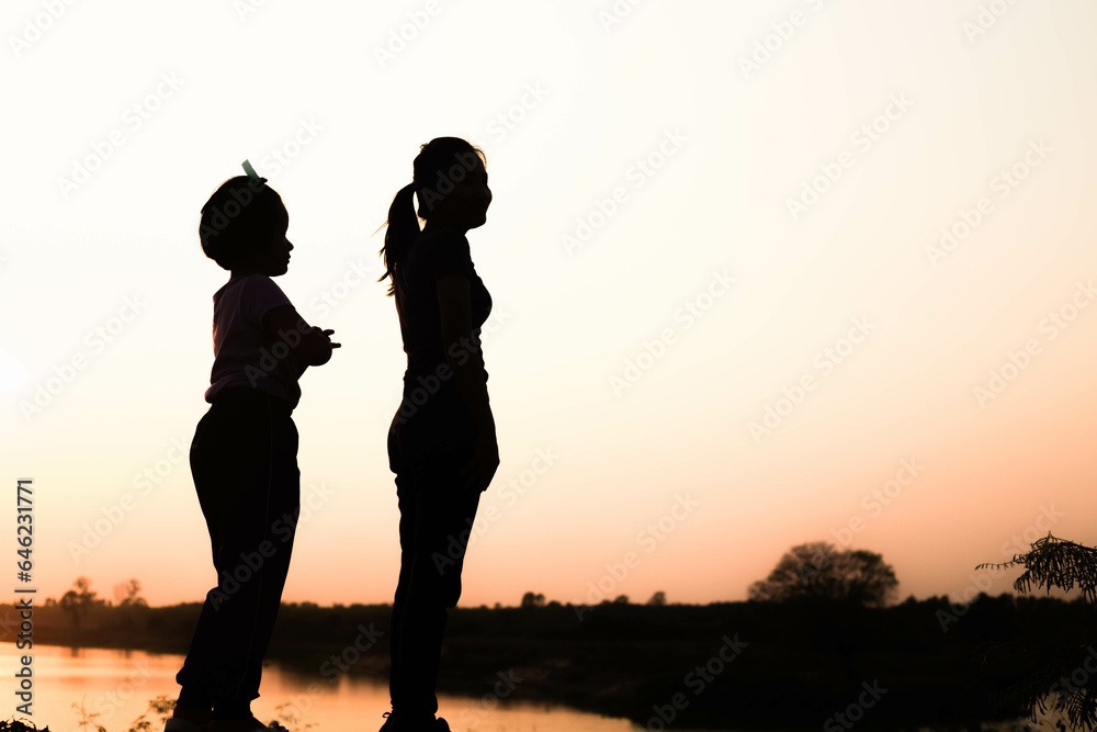 Silhouette of a family comprising a father, mother and two children happy family the sunset.Concept of friendly Silhouette of a family comprising a father, mother and two children happy family the sunset.Concept of friendly