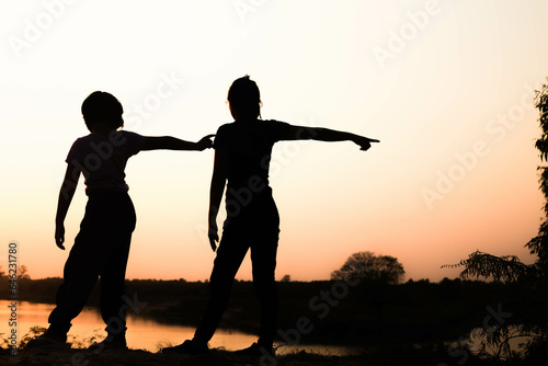 Silhouette of a family comprising a father, mother and two children happy family the sunset.Concept of friendly 