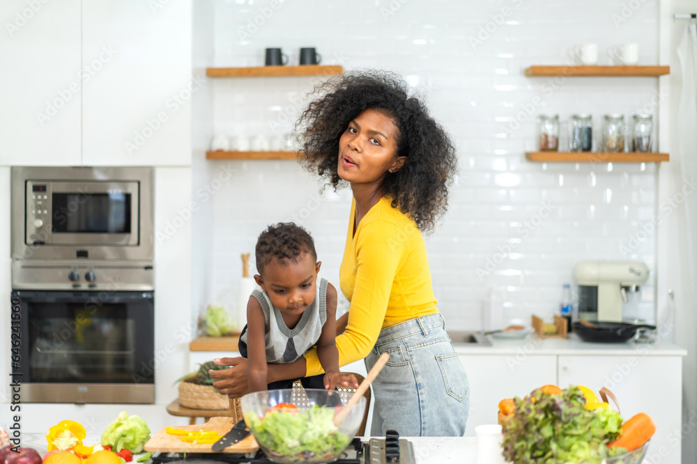 Portrait of enjoy happy love african american family mother and african little boy son child having fun help cooking food healthy eat together with fresh vegetable salad and ingredient in kitchen Portrait of enjoy happy love african american family mother and african little boy son child having fun help cooking food healthy eat together with fresh vegetable salad and ingredient in kitchen