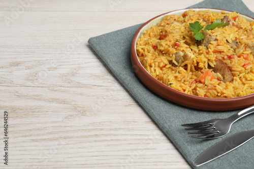 Delicious pilaf with meat served on white wooden table. Space for text