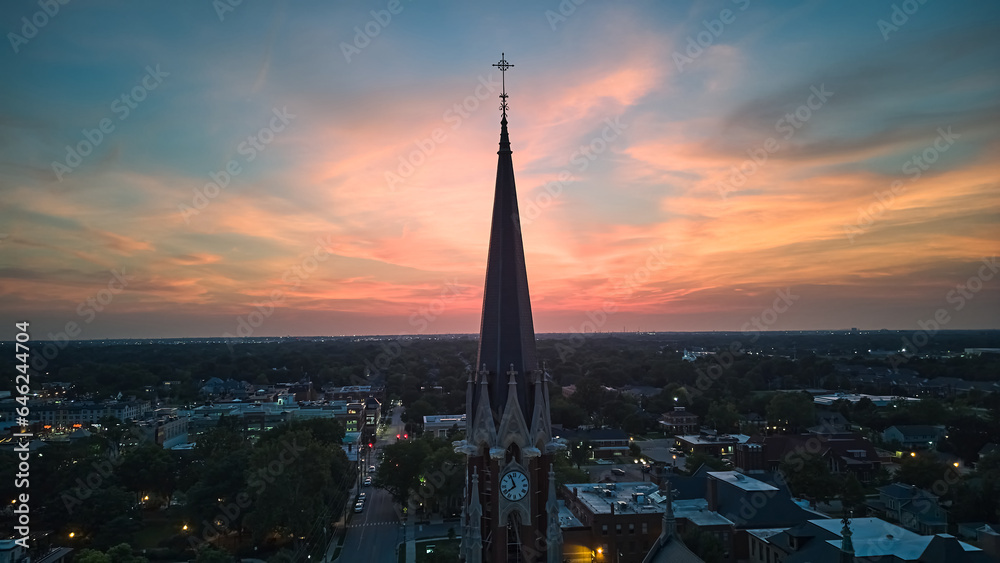 Fototapeta premium The silhouette of the cross and church bell tower in sunrise, sunset time. Aerial shot