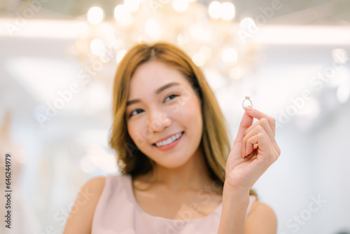 Attractive young bride is smiling and bride holding a ring in modern wedding salon.