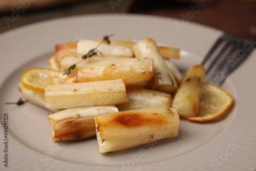 Baked salsify roots, lemon and thyme on plate, closeup