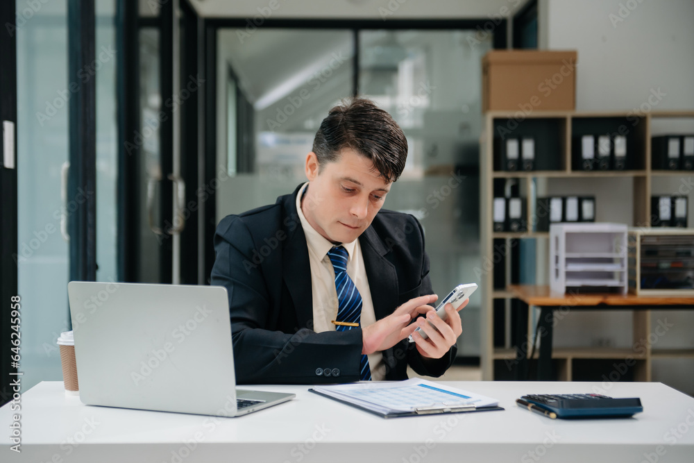 Young business man working at office with laptop, tablet and taking notes on the paper.. Young business man working at office with laptop, tablet and taking notes on the paper..