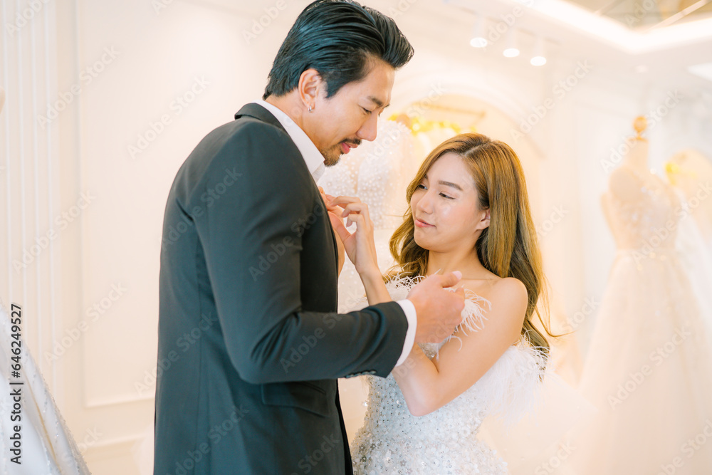 Attractive Bride and groom is smiling while choosing wedding dress in modern wedding salon. Attractive Bride and groom is smiling while choosing wedding dress in modern wedding salon.