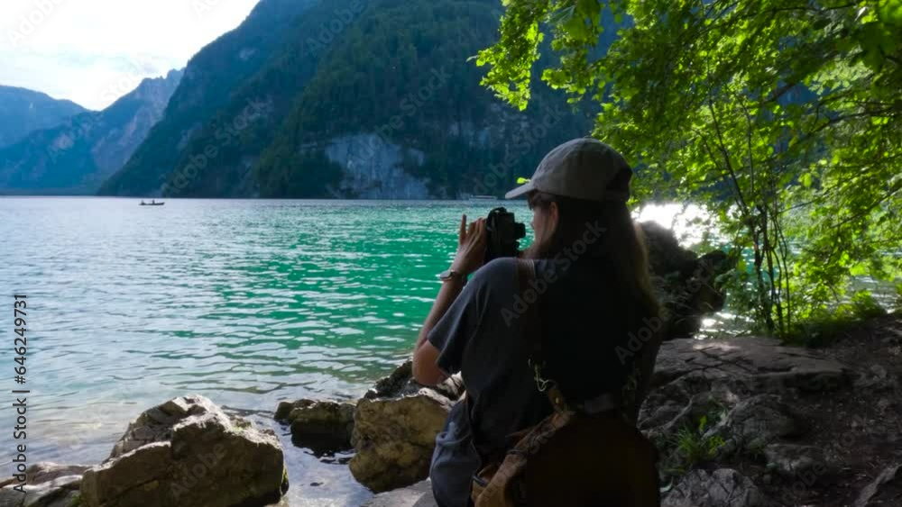 Tourist woman taking a photo with a camera in the shore of the King's Lake, Königssee in Germany, Bavaria. Surrounded by nature. Tourist woman taking a photo with a camera in the shore of the King's Lake, Königssee in Germany, Bavaria. Surrounded by nature.