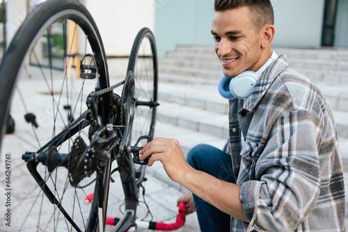 Smiling young man fixing a problem with a bike wheel