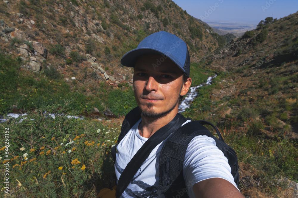 Selfie of a white Caucasian male tourist with a beard on a hike in the Kaskasu gorge by the river in the mountains in summer