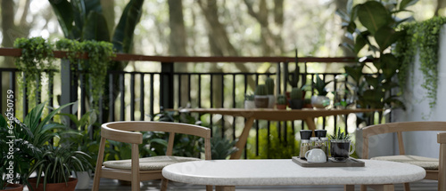 Schilderij op canvas Coffee table and armchairs on a green balcony relaxation space with various tropical plants