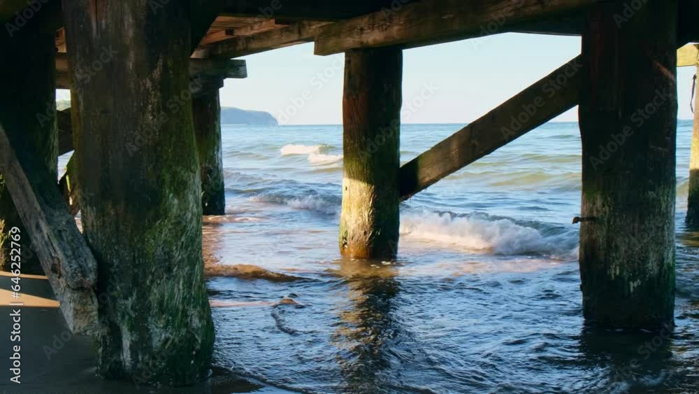 Storm sea waves under wooden pier in background design. Seascape with running splashing sea waves. Sandy beach vacation getaway in Gdansk Poland Storm sea waves under wooden pier in background design. Seascape with running splashing sea waves. Sandy beach vacation getaway in Gdansk Poland