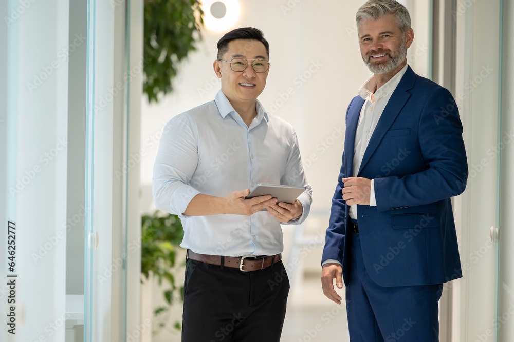Men standing in corridor in office and talking about their work.
