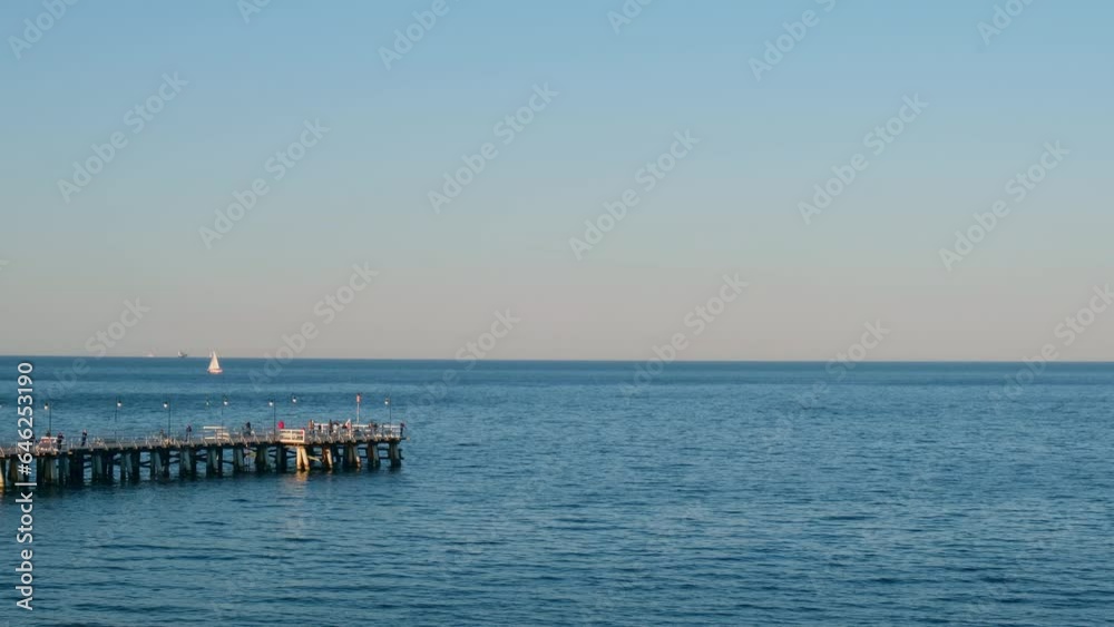 Storm sea waves empty wooden pier in dramatic blue sky background. Seascape with running splashing sea waves. Sandy beach vacation getaway in Gdansk Poland. Copy space for your text Storm sea waves empty wooden pier in dramatic blue sky background. Seascape with running splashing sea waves. Sandy beach vacation getaway in Gdansk Poland. Copy space for your text