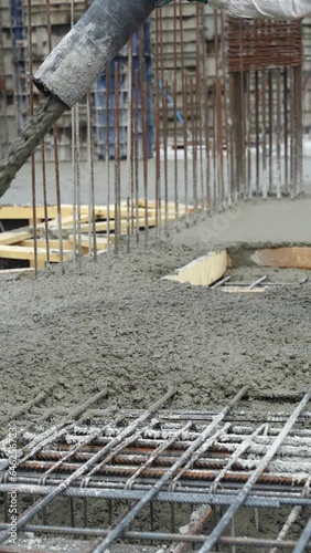 Iron grate or reinforcement on the ground poured with concrete from a pipe at a construction site