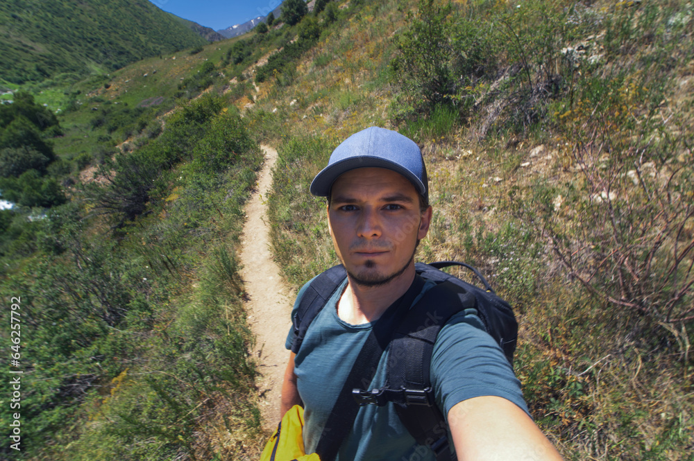 selfie of caucasian bearded male tourist traveler in a valley in the mountains in summer selfie of caucasian bearded male tourist traveler in a valley in the mountains in summer
