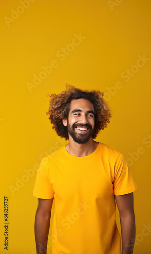 Casual studio portrait of young bearded man in yellow t-shirt casually smiling © IBEX.Media