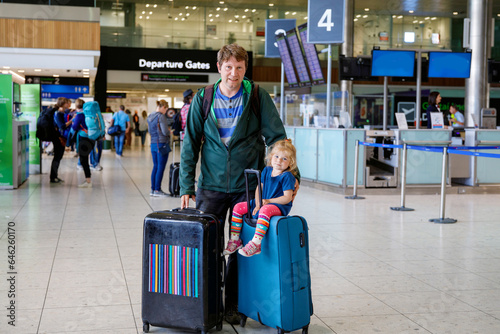 Cute little toddler girl and father at the airport. Happy family traveling by plane, making vacations. Young dad and baby daughter with suitcases waiting for flight. Family going on journey. Ireland