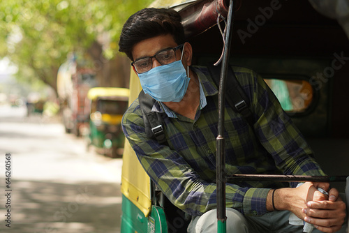 Young Indian middle class young man travelling in auto rickshaw using face mask © Karan