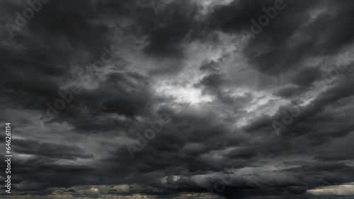 dark dramatic sky with black stormy clouds before rain or snow as abstract background, extreme weather, the sun shines through the clouds, high contrast photo