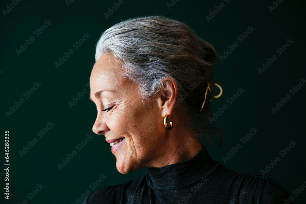 Smiling woman with gray hair in front of wall Smiling woman with gray hair in front of wall