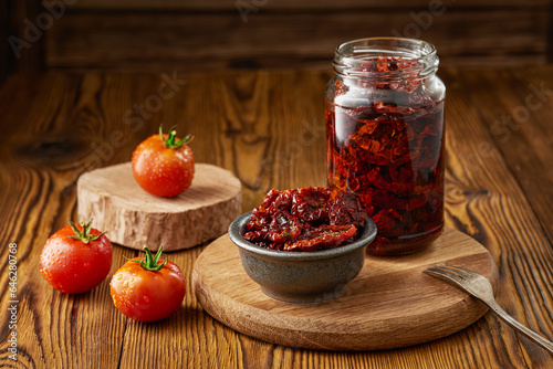 Fotografie Glass jar and bowl of sun-dried tomatoes in olive oil and fresh tomatoes