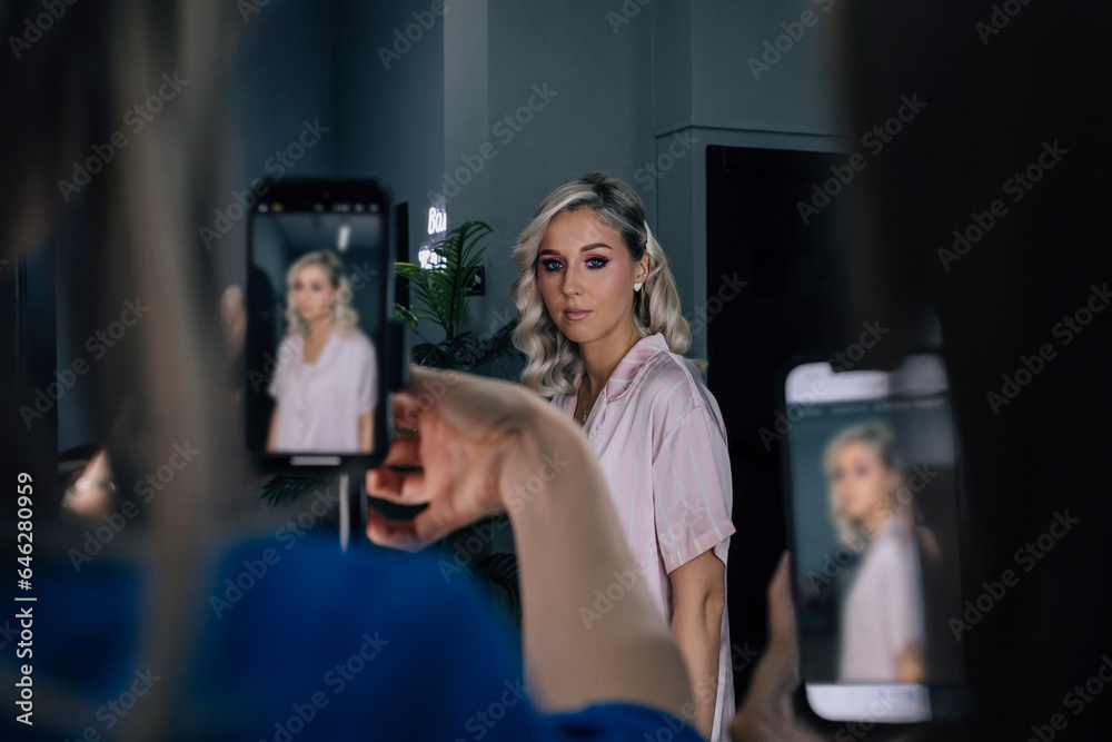 Make-up artist photographing client with smart phone in salon Make-up artist photographing client with smart phone in salon