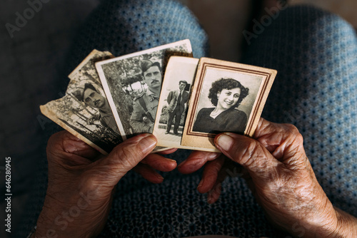 Hands of woman holding photographs from past at home