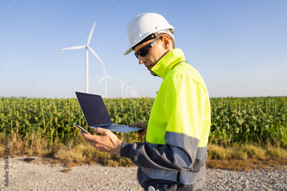 Engineer holding laptop and using smart phone on sunny day Engineer holding laptop and using smart phone on sunny day