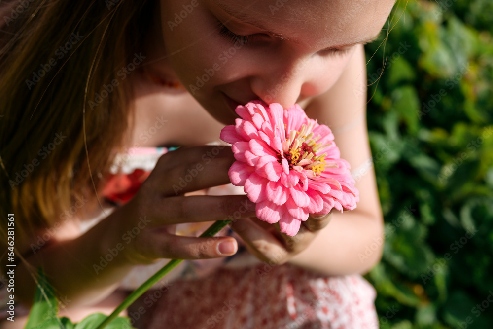 Girl holding and smelling pink flower in garden Girl holding and smelling pink flower in garden