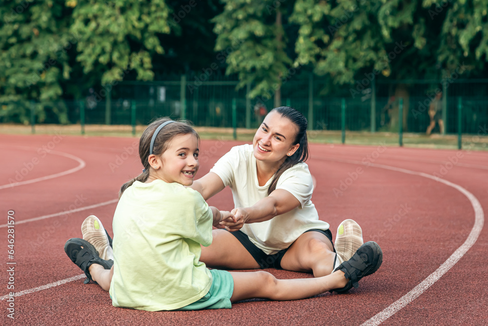 Caucasian woman and little girl are engaged in fitness at the stadium. Caucasian woman and little girl are engaged in fitness at the stadium.