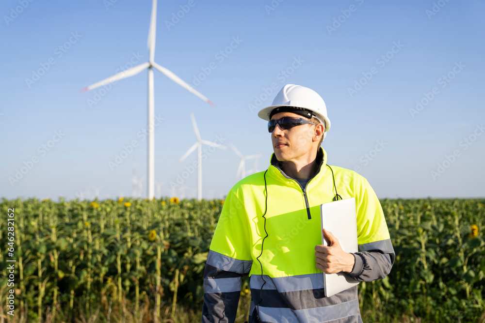 Engineer with laptop standing in front of field on sunny day Engineer with laptop standing in front of field on sunny day