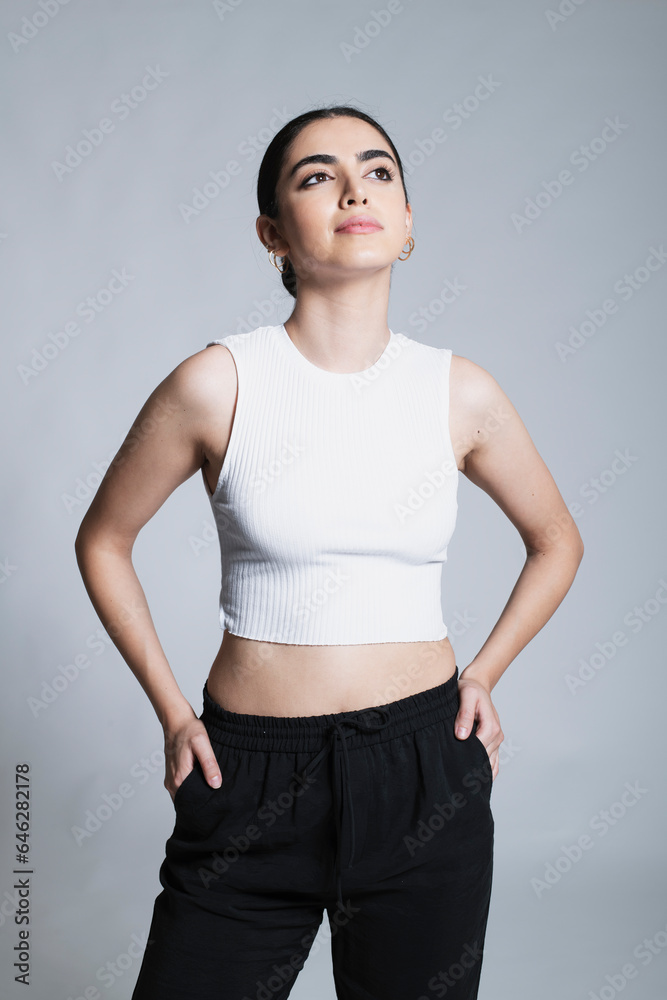 Thoughtful young woman with hands in pockets against white background Thoughtful young woman with hands in pockets against white background