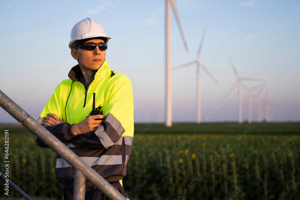 Engineer with arms crossed in front of wind turbine farm Engineer with arms crossed in front of wind turbine farm
