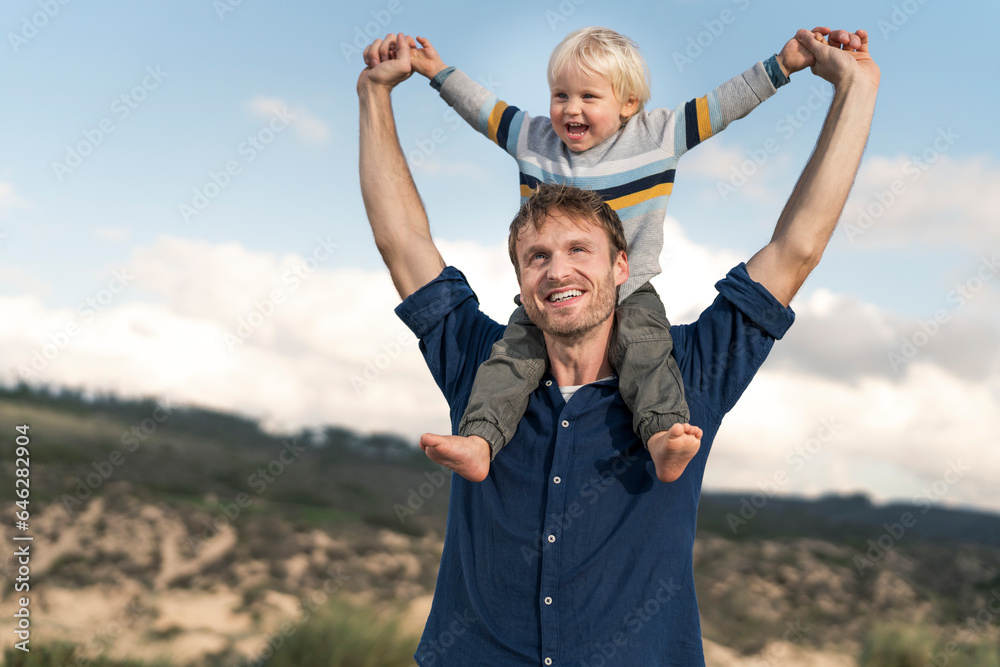 Smiling father carrying son on shoulders at beach Smiling father carrying son on shoulders at beach