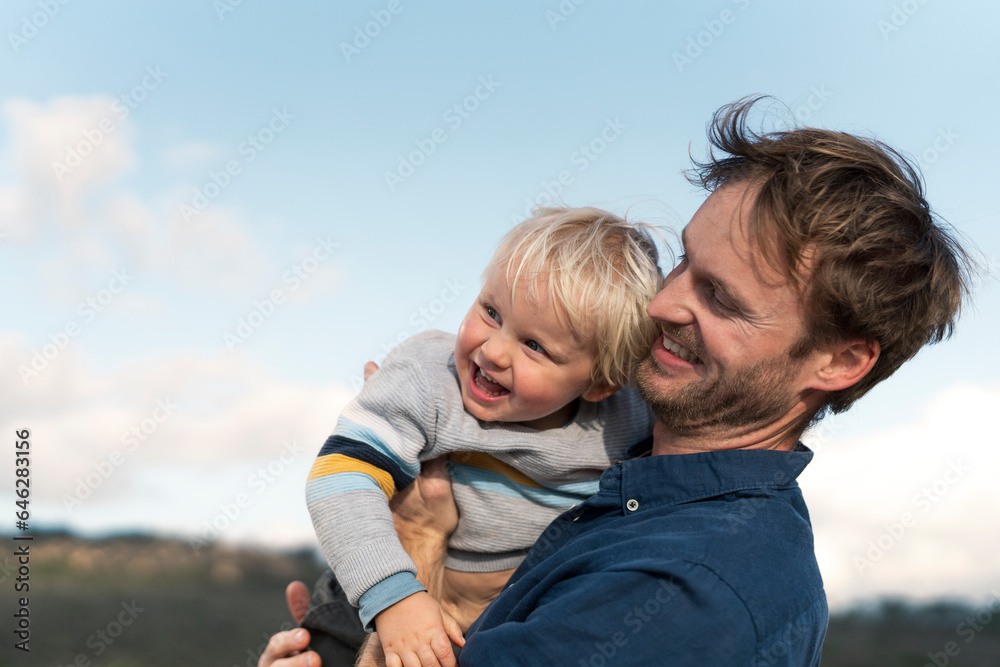 Happy father holding son under sky Happy father holding son under sky