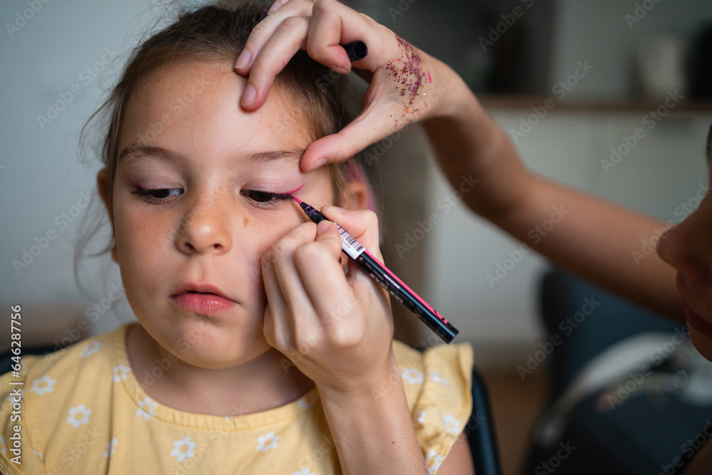 Close-up of makeup artist doing kids makeup with pink eyeliner. Small girl party or birthday day preparation. Close-up of makeup artist doing kids makeup with pink eyeliner. Small girl party or birthday day preparation.
