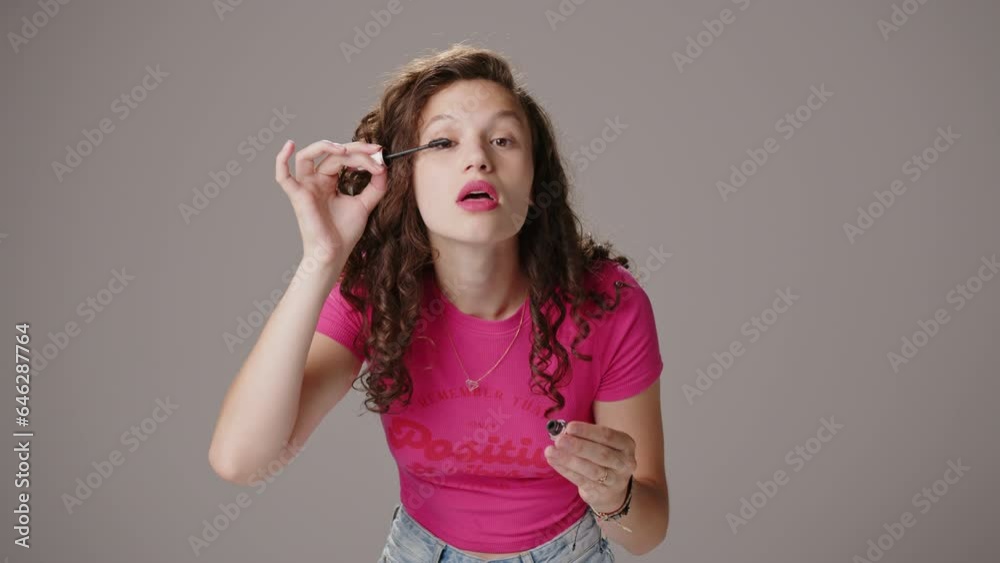 Beautiful young female model with long curly brown hair does the makeup and smiles. Beautiful young female model with long curly brown hair does the makeup and smiles.