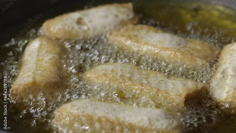 Close-up of deep frying tofu in boiling oil. vegan and vegetarian food Close-up of deep frying tofu in boiling oil. vegan and vegetarian food