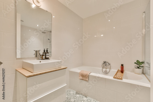 a bathroom with tiled flooring and white tiles on the walls there is a large mirror above the bathtub