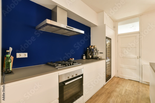 a kitchen area with blue walls and white cupboards on either side, there is an oven in the corner © Casa imágenes