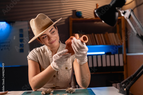 Archeologist working with antique vessel late night in office