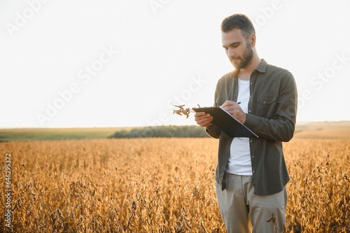 Portrait of farmer standing in soybean field at sunset.
