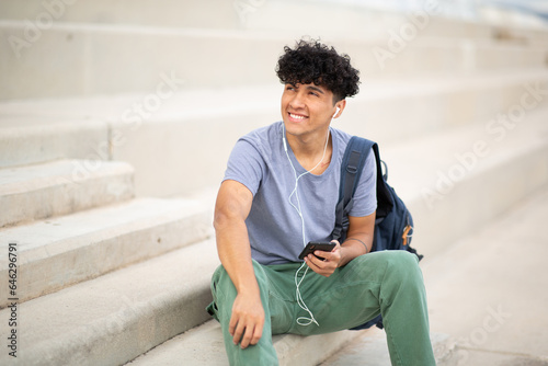 smiling young man listening to music with headphones and mobile phone