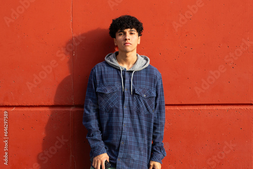 cool young guy standing by red wall