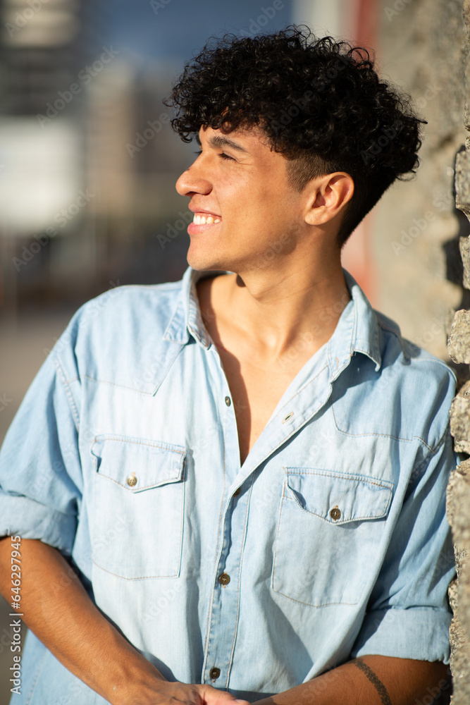 smiling young man leaning against wall and looking away smiling young man leaning against wall and looking away