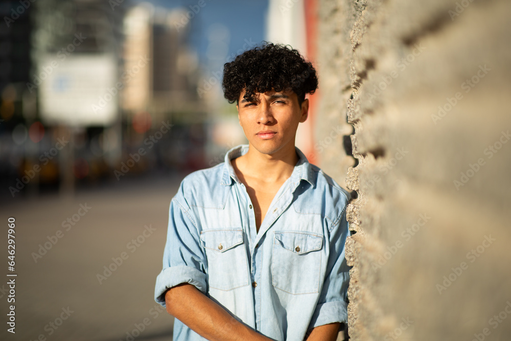cool young guy leaning against wall by city street cool young guy leaning against wall by city street