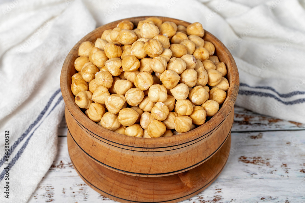 Roasted hazelnuts in wood bowl. Peeled hazelnuts kernel on white wood background. Close up Roasted hazelnuts in wood bowl. Peeled hazelnuts kernel on white wood background. Close up