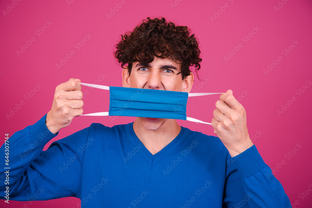 Young attractive student posing on a pink background with a protective mask. Young attractive student posing on a pink background with a protective mask.
